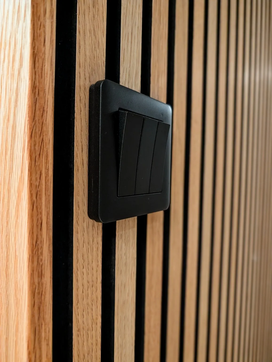 Svart strömbrytare på träpanel